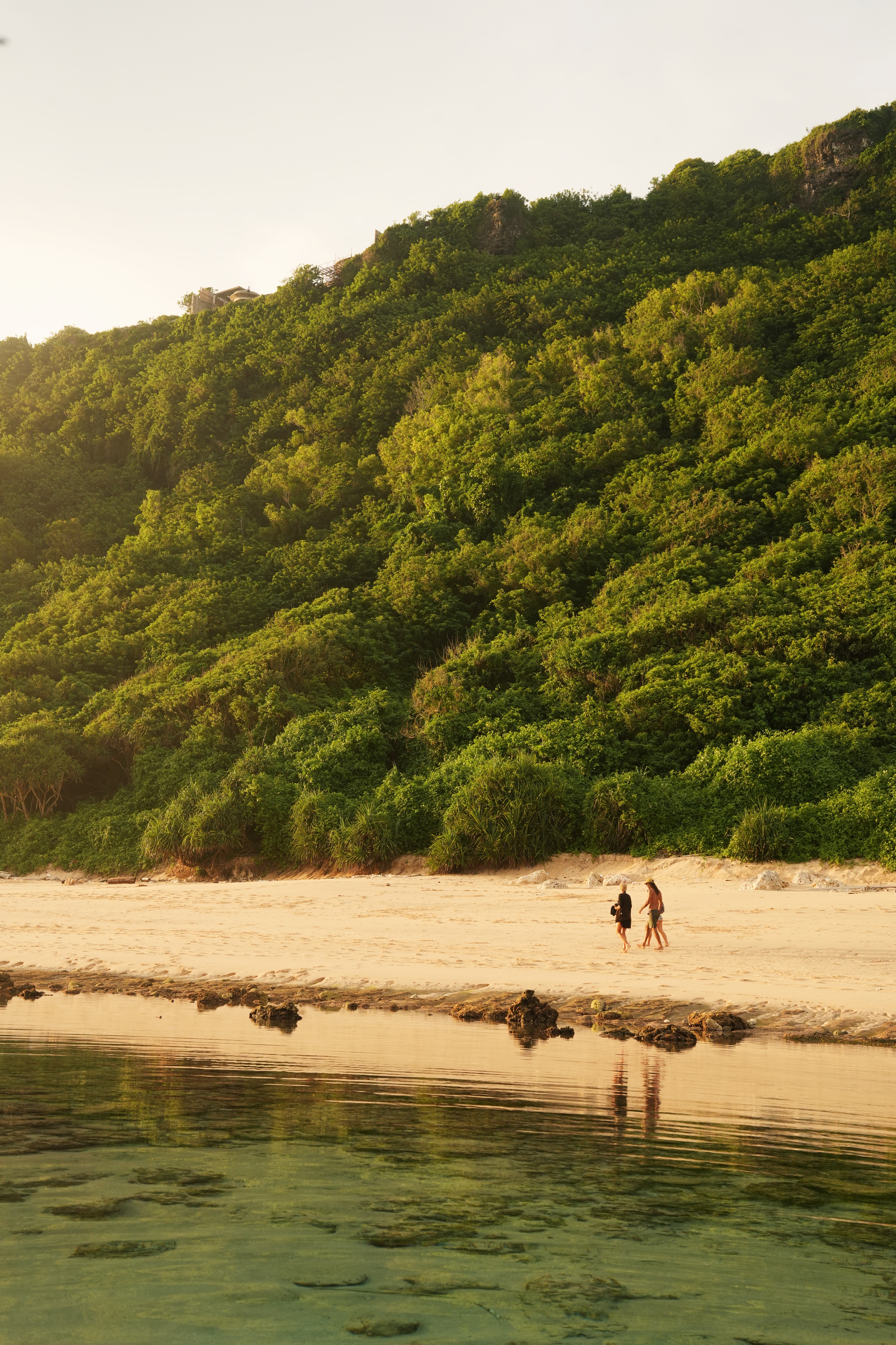 Two people walking on beach at sunset